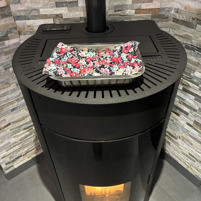 Bouillotte sèche aux graines de lin bio de la marque Un Amour de Lin, posée sur un lèche frite sur un système de chauffage poêle à granulés